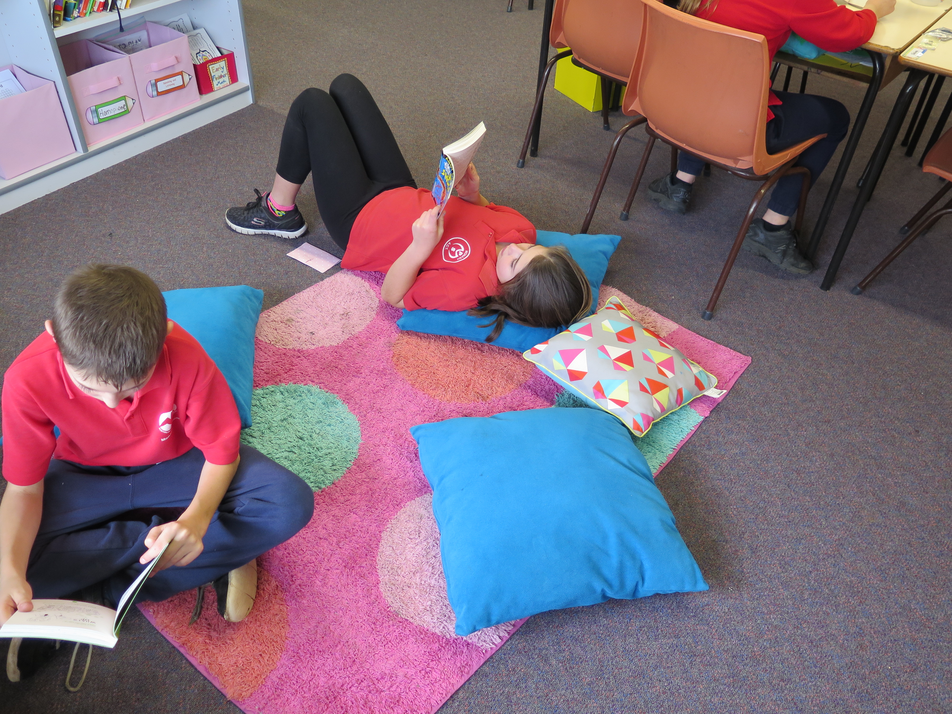 Students reading their new books on the floor. 